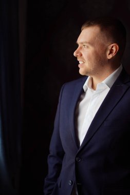 Karanlık bir odada ceketli bir adamın portresi..