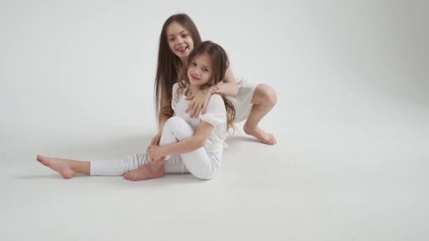 Kleine Mädchen mit langen Haaren in weißen Kleidern spielen, frönen und kämpfen — Stockvideo