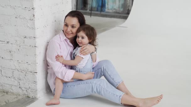 Belle famille heureuse assis sur le sol et câlin dans le studio photo blanc. dans les coulisses. — Video