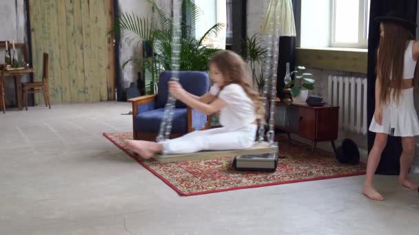 Deux sœurs montent sur une balançoire dans le loft. séance photo dans un studio photo. — Video