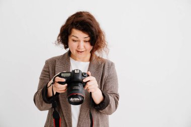 Kareli ceketli mutlu esmer kadın kameradaki resimlere bakıyor. 