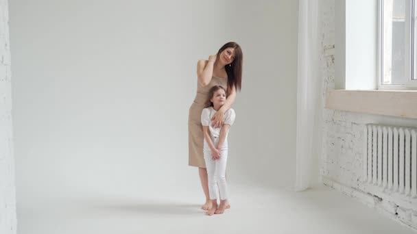 Mãe e filha posar em um estúdio de fotografia branca para uma sessão de fotos. bastidores. — Vídeo de Stock