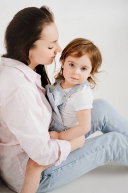 Güzel, mutlu bir aile yerde oturup beyaz fotoğraf stüdyosunda sarılır. sahne arkası.