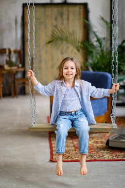 Çocuk dairede salıncakta sallanıyor. Çocuk giyim mağazası