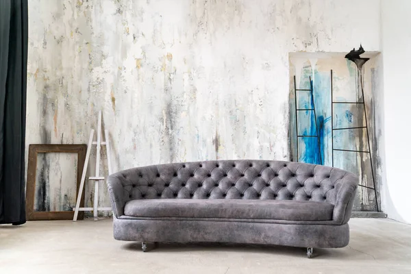 Loft interior. stylish grey sofa against gray wall with unusual colored plaster.