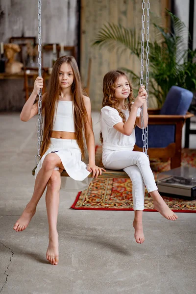 Dos hermosas chicas paseos en columpio. habitación original de los niños — Foto de Stock