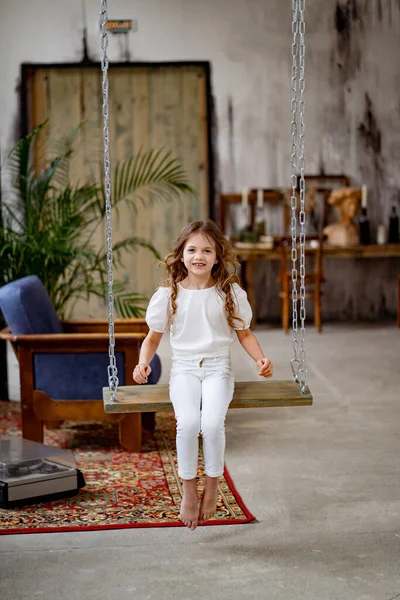 Chica bonita en ropa blanca paseos en columpio. habitación original de los niños — Foto de Stock