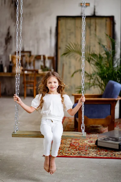 Menina bonita em roupas brancas passeios no balanço. quarto original das crianças — Fotografia de Stock