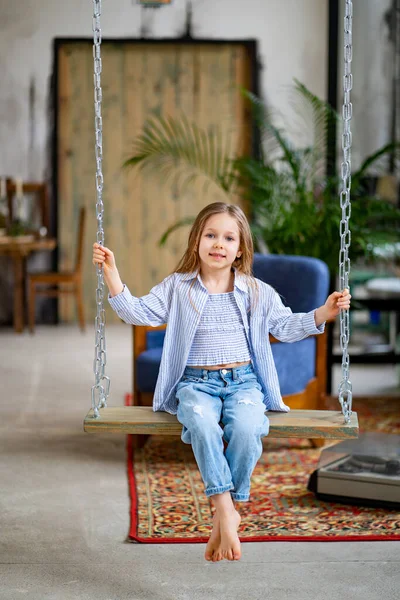 La niña cabalga en un columpio en el desván. tienda de ropa para niños —  Fotos de Stock