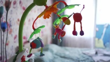 Parlak oyuncakları olan cep telefonu beşikteki çocuk odasında dönüyor. pencereye karşı