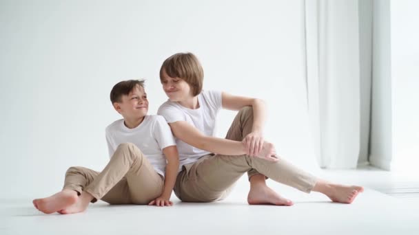 Dois meninos de camisetas brancas posam para um fotógrafo em um estúdio de fotos. — Vídeo de Stock