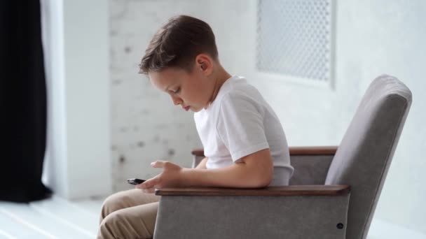 Egy tinédzser fiú fehér pólóban okostelefonnal a kezében.. — Stock videók