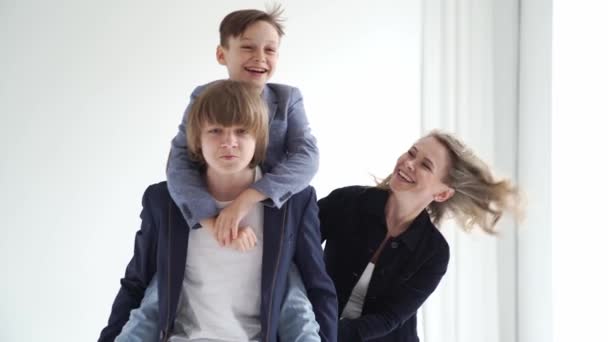 Uma mãe com dois filhos em roupas azuis se divertir e posa para uma sessão de fotos — Vídeo de Stock