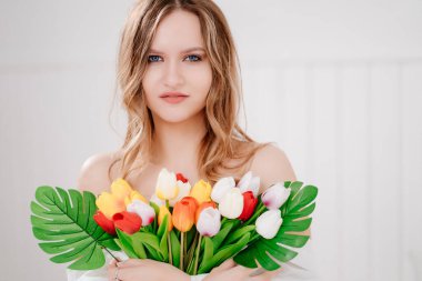 Renkli lalelerle dolu buketi olan güzel genç bir kadın.