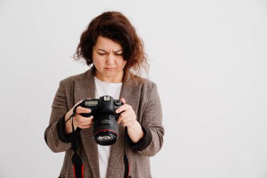 Kareli ceketli esmer kadın kameradaki resimlere bakıyor. 