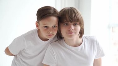 Beyaz tişörtlü iki çocuk fotoğraf stüdyosunda bir fotoğrafçıya poz veriyor..