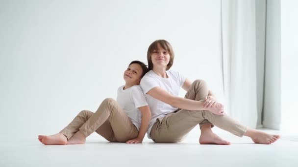 Twee jongens in witte T-shirts poseren voor een fotograaf in een fotostudio. — Stockvideo