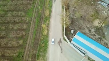 Araba köy yolu boyunca tarımsal binalar ve bahçeler boyunca gidiyor.. 