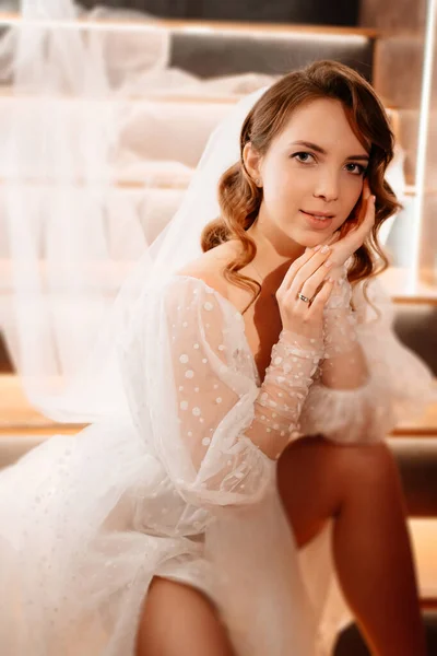 La novia en un vestido blanco de pie en la escalera mal iluminada — Foto de Stock