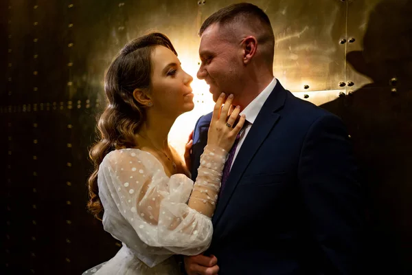 Bridegroom and bride in a elegant dress in a dark corridor — Stock Photo, Image