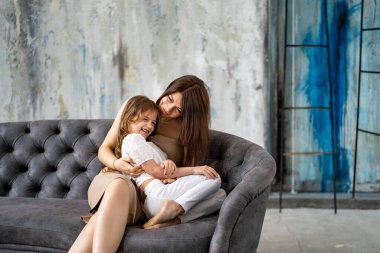 Anne kanepede kızına sarılıyor. Mutlu aile. 