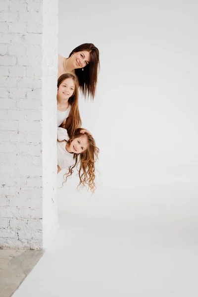 Mamá e hijas posan en un estudio de fotografía en blanco. productos para el cuidado del cabello. — Foto de Stock