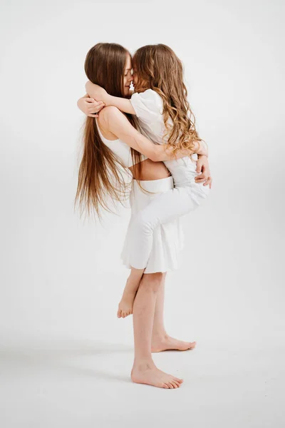 Zwei fröhliche Mädchen mit langen Haaren in weißen Kleidern spielen, haben Spaß. — Stockfoto