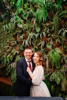 Mutlu gelin ve damat duvarda canlı bitkilerle süslenmiş.. 