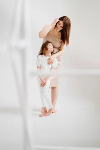 Mamá y su hija posan en un estudio de fotografía en blanco. — Foto de Stock