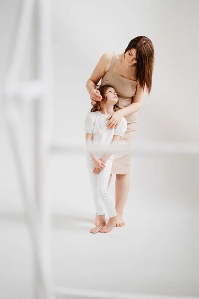 Mamá y su hija posan en un estudio de fotografía en blanco. — Foto de Stock