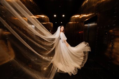 Beyaz, zarif elbiseli, duvağı olan güzel gelin karanlık bir koridorda yürür.