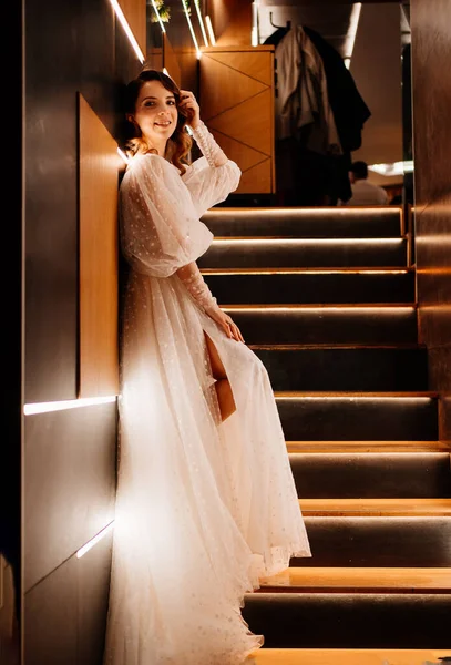하얀 드레스를 입은 신부가 조명 이 잘 안 된 계단 위에 서 있는 모습 — 스톡 사진