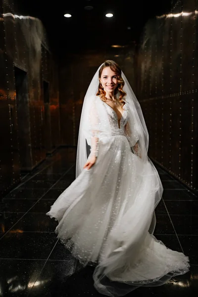Красива наречена в білій елегантній сукні, з вуаллю спускається в темний коридор — стокове фото