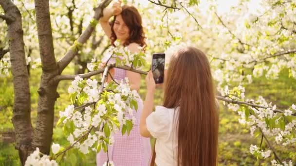 Дочка фотографує на телефоні матерів у квітковому саду . — стокове відео