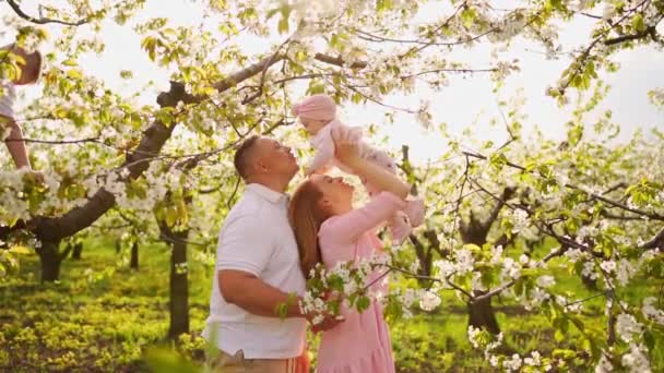 Familia con una hija en el jardín de flores de primavera. labio leporino en lactantes. — Vídeos de Stock