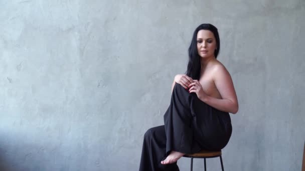 Une belle femme seins nus assise sur une chaise haute. — Video