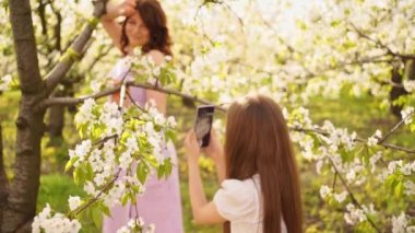 Kızı çiçeklenme bahçesinde annesinin telefonuyla fotoğraf çekiyor..