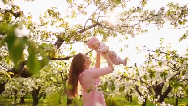 開花期の庭で子供を持つ母親。左のクリップを持つ子供の手術. — ストック動画