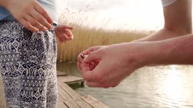 Eller. Adam çocuğun oltaya solucan takmasına yardım ediyor. Balıkçılar