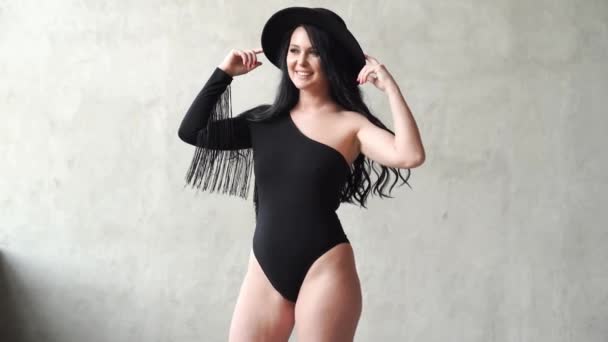 Donna sexy in un body nero e cappello al muro grigio. servizio fotografico dietro le quinte — Video Stock