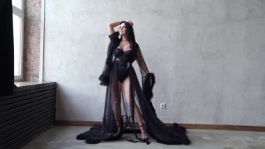 Gri duvarda duran siyah elbiseli güzel ve seksi bir kadın..