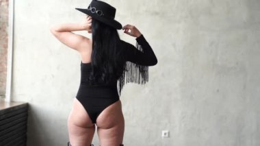 Dikiz aynası. Gri duvarda siyah takım elbiseli ve şapkalı güzel ve seksi kadın.