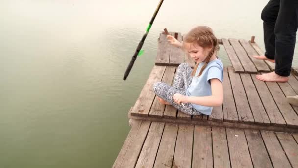 Der Junge hilft dem Mädchen, den gefangenen Fisch vom Haken zu nehmen. — Stockvideo