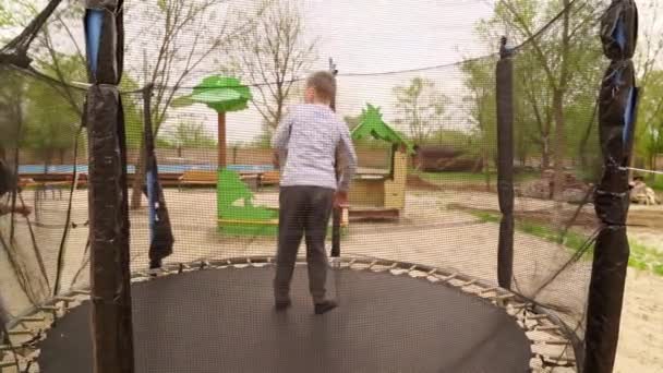 Ten kluk skočí na trampolínu. zábava pro děti venku. — Stock video