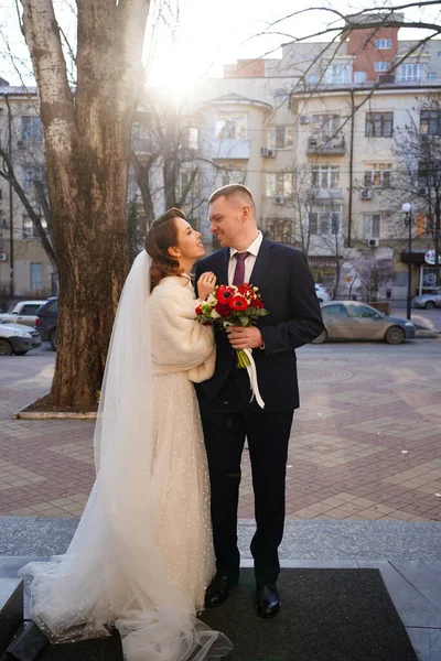 新婚旅行だよ。花嫁は優しくレジストリオフィスの前で新郎を抱擁し — ストック写真