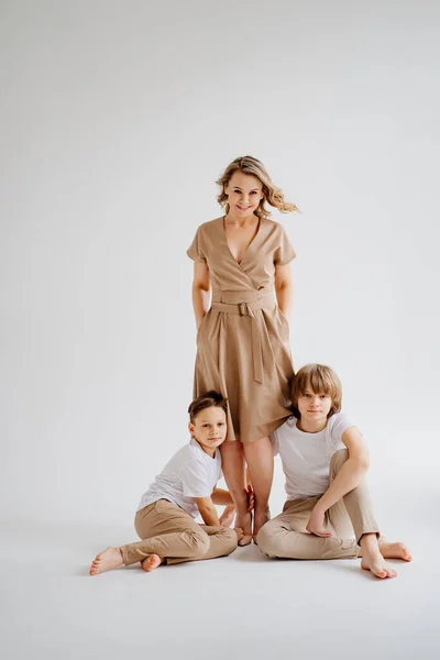 Une mère et ses deux fils en vêtements beige et blanc posent pour une séance photo — Photo