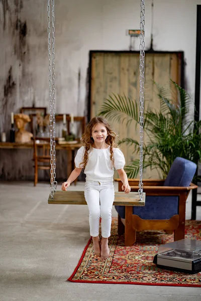 Chica bonita en ropa blanca paseos en columpio. habitación original de los niños —  Fotos de Stock