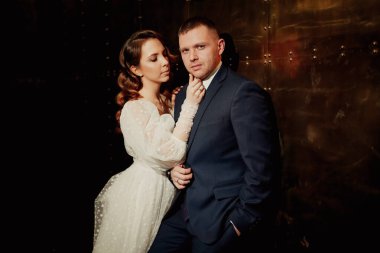 Gelin ve damat, karanlık bir koridorda zarif bir elbise içinde.