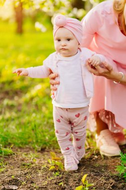 İlk adımlar. Anne ve küçük kızı çiçek bahçesine gider. Bebeklerde yarık dudak.