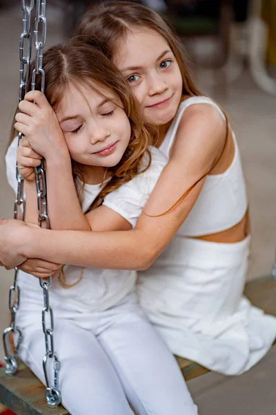 Pretty girls in white clothes rides on swing. childrens friendship. — Stock Photo, Image